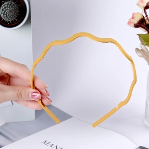 Detail of yellow wavy plastic headband with fine teeth for a non-slip secure hair grip