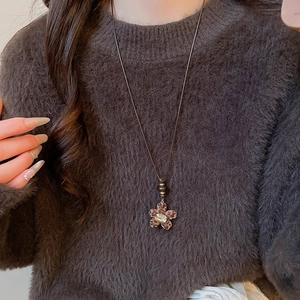 Close-up of leopard print flower pendant necklace with crystal on brown sweater