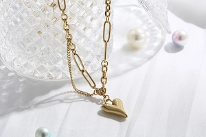 Dettaglio di una collana dorata a doppio strato con ciondolo a cuore su tessuto