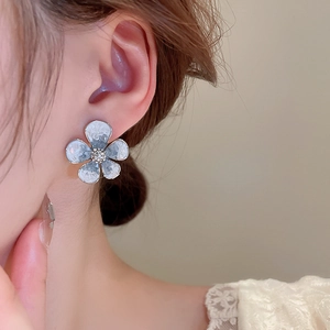 Close-up of blue gradient crystal flower earring with rhinestones worn by a model