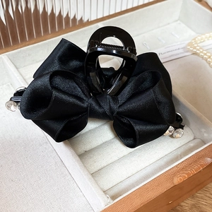 Detail of black satin ribbon hair claw clip with rhinestones in a beige velvet jewelry box