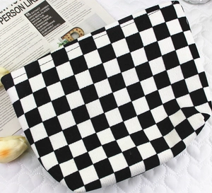 Detail of black and white checkered corduroy makeup bag on a quilted soft background