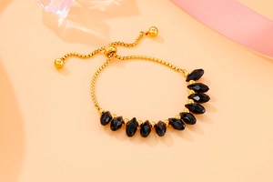 Detail of adjustable gold box chain bracelet featuring black teardrop crystals and ball clasp