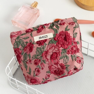 Macro shot of pink floral jacquard cosmetic bag with rose pattern and woven label