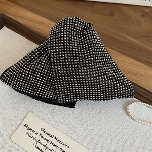 Close-up of black acrylic triangle claw clip with rhinestones on a white marble tray