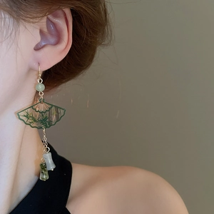 Close-up of elegant fan-shaped earrings with bamboo patterns and green jade-like beads