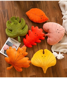 Flat lay of colorful leaf-shaped plush cushions on wood floor with cozy home decor