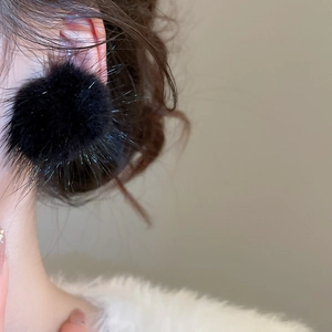 Vue détaillée de boucles d'oreilles pompon noir en peluche pour un style automne-hiver