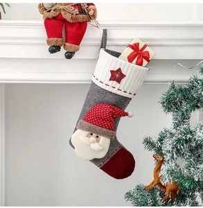 Détail d'une chaussette de Noël grise avec Père Noël 3D sur une cheminée blanche