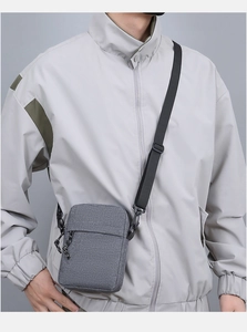 Grey nylon crossbody phone bag shown on model with adjustable black shoulder strap