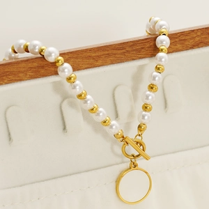 Dettaglio della collana di perle con chiusura OT e ciondolo a cerchio in metallo