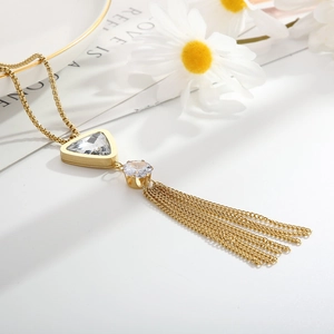 Detail of gold long tassel necklace with crystal triangle pendant and dainty daisy decor