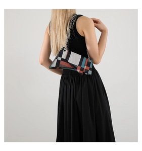 Close-up of geometric puzzle pattern handbag with silver chain on black dress