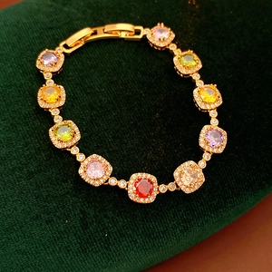 Close-up of vintage gold bracelet with colorful square zircons on green velvet