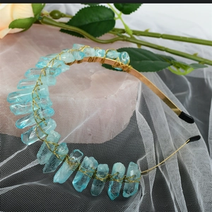 Macro detail of blue raw crystal crown with gold wire weaving and floral background