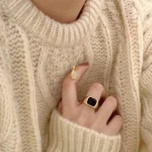 Detail of 925 silver gold-plated necklace with oval white stone on warm knit sweater
