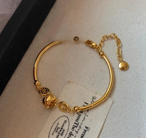 Detailed view of 18K gold plated bamboo link bracelet with geometric bell charm