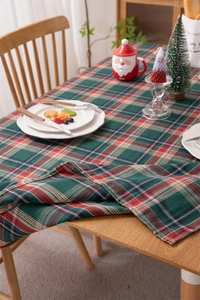 Macro detail of red and green festive plaid tablecloth with gold thread and tassels