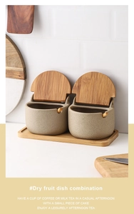 Detailed view of beige ceramic seasoning jars with bamboo lids and spoons on wooden tray