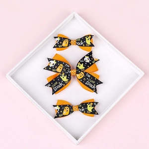 Detailed view of Halloween themed orange and black ribbon hair clips with ghost prints