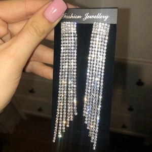 Close-up of silver rhinestone long tassel earrings held in hand with jewelry card