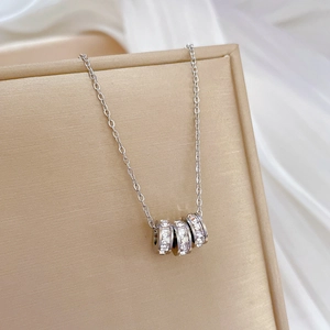 Macro shot of silver titanium steel necklace with three pavé diamond-set ring pendants