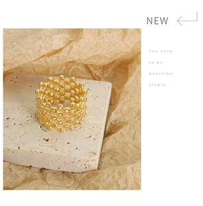 Detailed view of hollow lattice gold ring with crystals on a textured stone tray