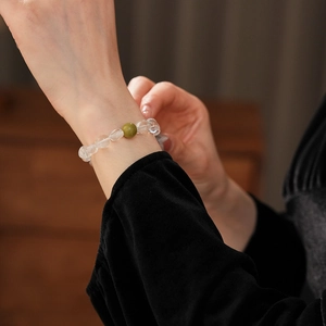 Détail de perles de cristal et bracelet en pierre de santal vert sur un poignet de femme