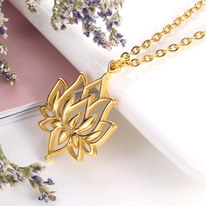 Macro shot of polished gold lotus flower pendant necklace on white surface with lavender