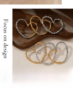 Macro detail of textured heart-shaped hoop earrings in gold and silver finishes