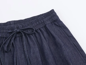Detailed macro view of the elastic drawstring waistband on dark blue denim trousers