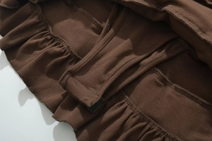 Close-up of brown knit fabric showing ruffled hem and detailed stitching on a mini dress