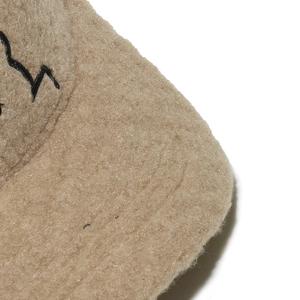 Macro shot of light brown faux lamb wool fabric with dense texture and black embroidery