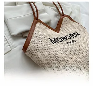 Detail of woven straw bucket bag with MOBORN PARIS embroidery and brown leather trim