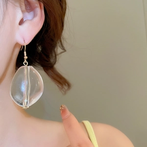 Close-up of gold hook earring featuring a clear acrylic organic resin drop pendant
