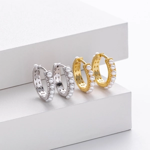 Detail view of gold and silver S925 sterling silver huggie earrings with pearl inlay