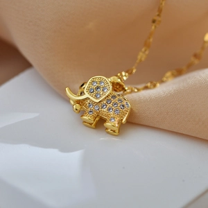 Elegant gold elephant necklace with sparkling crystals on a pink textured background