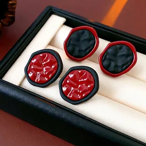 Boucles d'oreilles géométriques avec résine rouge et noire sur présentoir de bijoux