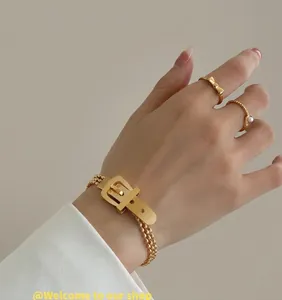Close-up of 18K gold plated belt buckle bracelet and bow ring on hand