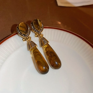 French vintage teardrop earrings with tiger eye resin and rhinestones on a ceramic dish