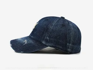 Detail view of distressed denim baseball cap with vintage frayed holes and side profile