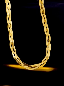 Macro view of triple-layered woven titanium steel gold herringbone chain texture