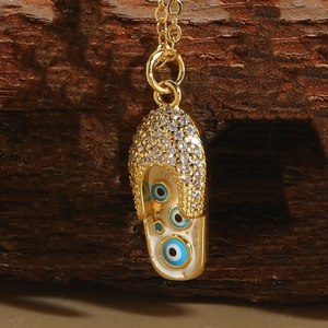 Macro shot of evil eye flip-flop pendant with gold plating and enamel inlay details
