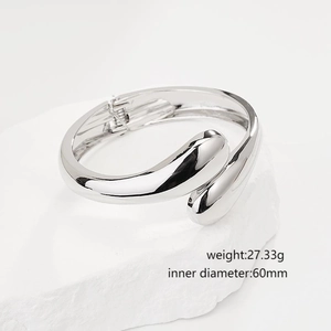 Minimalist silver geometric water drop bangle displayed on white rock aesthetic prop