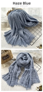 Detail view of haze blue crinkle scarf with frayed edges and textured fabric surface