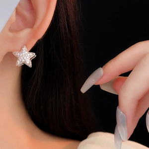 Detail of a sparkling zircon star earring worn by a model on a dark background