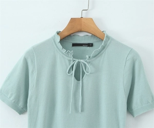 Dettaglio di un top in maglia verde menta con scollo rotondo, fiocco e bordo a volant