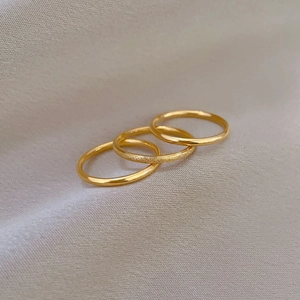 Detailed macro shot of three stackable gold rings in polished and matte titanium finishes