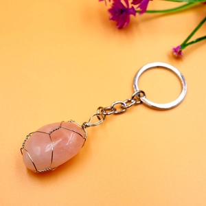 Detail of pink crystal stone wrapped in silver wire on a metal keychain pendant
