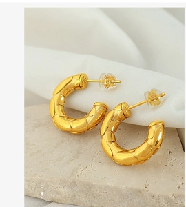 Detailansicht goldene Creolen mit Schlangenmuster-Prägung und Silikon-Ohrsteckern